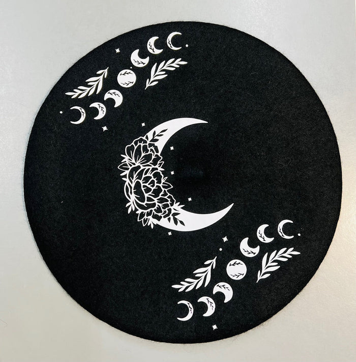 Black circular mat with white moon and leaf designs on a light gray background